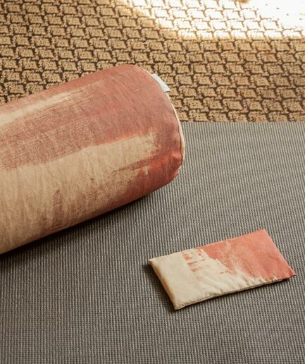 présentation de l'eye-pillow Aura rouge avec le bolster assorti sur tapis de yoga gris