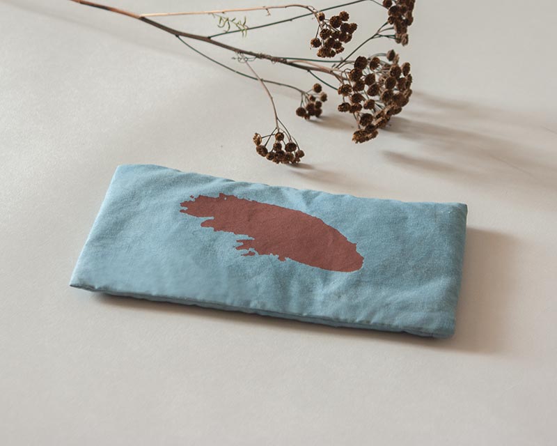 eye-pillow Shodô bleu et rouge avec fleur séchée posés dans un décor blanc