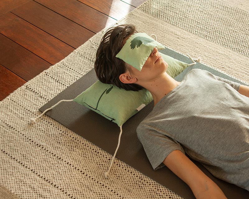 Anne allongée sur oreiller japonais avec l'eye pillow Shodô vert sur les yeux dans un salon