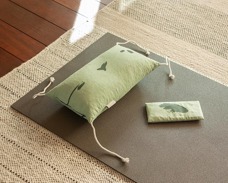 L'eye-pillow Shodô vert et l'oreiller japonais de la même collection posés sur tapis de yoga gris