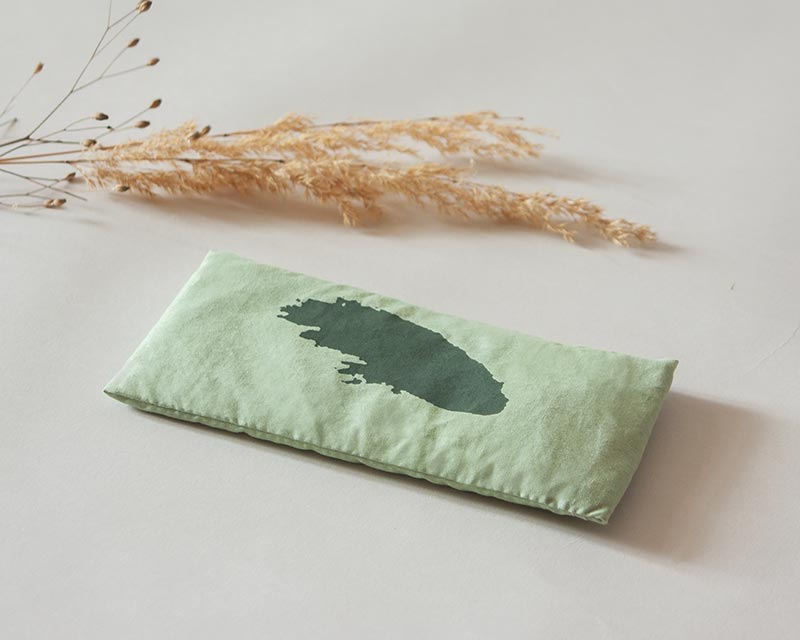 eye-pillow Shodô vert avec fleur séchée présenté dans un décor neutre