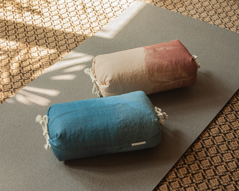 deux coloris de l'oreiller japonais Aura présentés sur un tapis de yoga dans un intérieur bohème