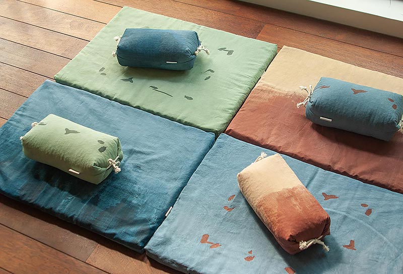 4 zabutons ou tapis de méditation posés sur un parquet avec des oreillers japonais